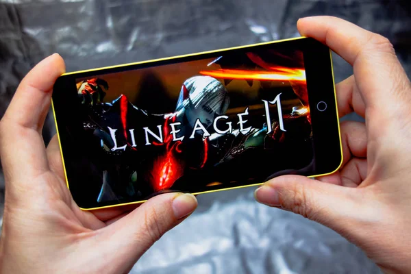 乌克兰伯迪扬斯克--2019年3月16日: 在显示屏上拿着带有血统2革命游戏的智能手机的手. — 图库照片