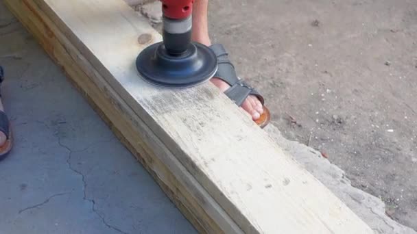 Een man poliert het bord met behulp van nozzles op de boor. Schuren van houten hout met schuurpapier. — Stockvideo