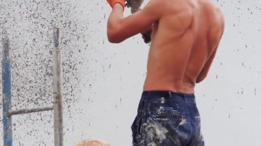 Bir erkek oluşturucu bir sokak duvarına bir sıva püskürtücü ile dekoratif terbiye uygular.