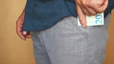Bir adam pantolon cebine euro banknotlar koyar. Bir adam cebinde para saklar..