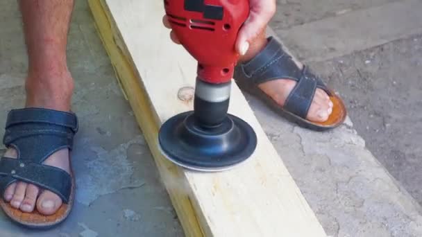 Een man poliert het bord met behulp van nozzles op de boor. Schuren van houten hout met schuurpapier. — Stockvideo