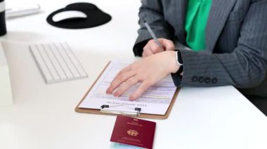 Kafkas bir kadının ofis masasında Alman pasaportuyla vize başvurusu formu doldurması. Yüksek kaliteli FullHD görüntüler