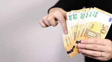 Elli avroluk nakit para tutan, siyah gömlek giyen, arka planda fotokopi alanı olan gri bir kadın. Yüksek kaliteli FullHD görüntüler