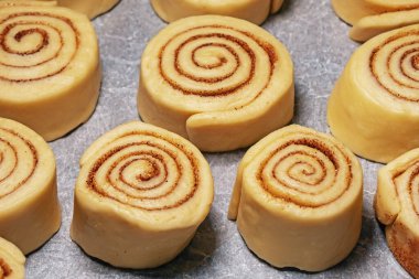 Hazırlık aşamasında ev yapımı tarçınlı çörekler. Salyangoz şeklinde ham hamur (spiral)