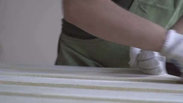 Wooden products are processed by the master in white gloves and a green apron. Working with wood. Beautiful things made of natural material. The process of making things out of wood sandpaper. — Stock Footage Wooden products are processed by the master in white gloves and a green apron. Working with wood. Beautiful things made of natural material. The process of making things out of wood sandpaper. Video Clip