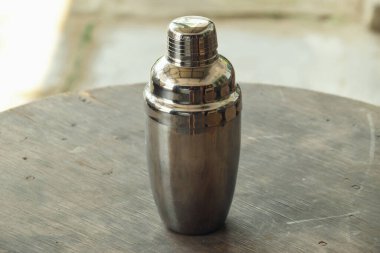 Genellikle Cocktail Shaker olarak adlandırılan içki yapmak için kullanılan bir araç geleneksel bir kafe ahşap masa üzerindedir..