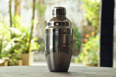 Bir kafenin doğal arka planına sahip ahşap bir masada, sıklıkla Kokteyl Sallayıcısı olarak adlandırılan içki yapmak için bir araç kapatın.