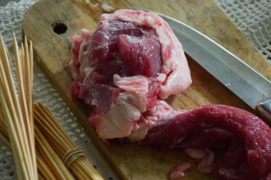 Kurbandan elde edilen ahşap bir üste taze keçi eti yakın çekim. Kurban Bayramı kutlamalarında tipik bir Endonezya yemeği olan ızgara satay haline getirilmeye hazır..