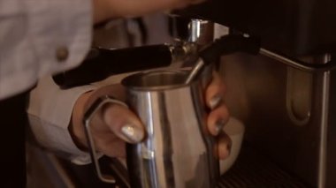 Süt bir profesyonel kahve makinesinde bir kavanoza kırbaçlanan Barista