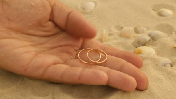 Anillos de boda de oro en la arena del mar — Vídeos de Stock