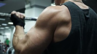 Sporcu spor elinde çalışır. O halter kaldırıyor ve pazı üzerinde çalışıyor.