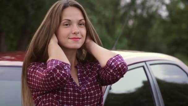 Een Lief Meisje Rechtzetten Haar Haar Tegen Een Rode Auto — Stockvideo