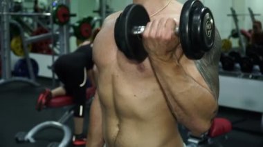 Atletik güçlü adam bir halter parlak bir spor salonunda kaldırdı.