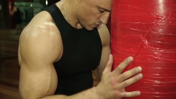 Jovem boxer suado está descansando em saco de perfuração — Vídeo de Stock