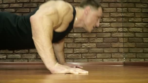 El hombre fuerte empuja hacia arriba desde el suelo en el gimnasio — Vídeo de stock