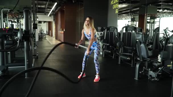 Atletische vrouwen actief in een sportschool oefeningen met Battle Ropes tijdens haar kruis fitnesstraining. Slow motion — Stockvideo