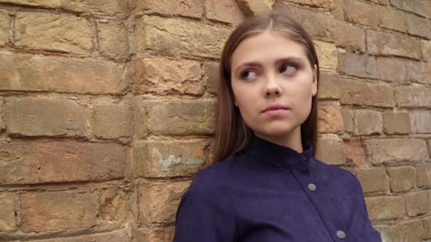 Meisje Blauwe Jurk Poseren Camera Tegen Een Bakstenen Muur Achtergrond — Stockvideo