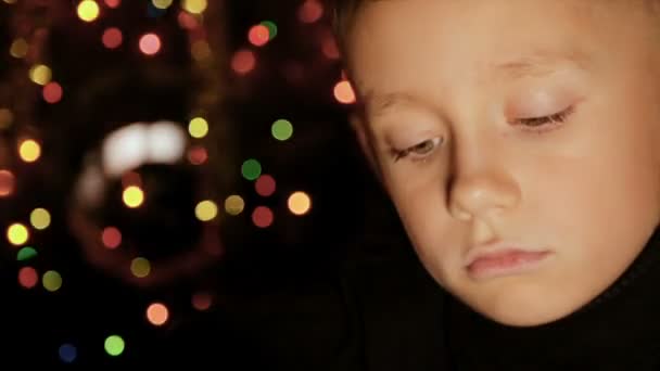 Retrato de un niño en el fondo de las luces de Navidad — Vídeos de Stock