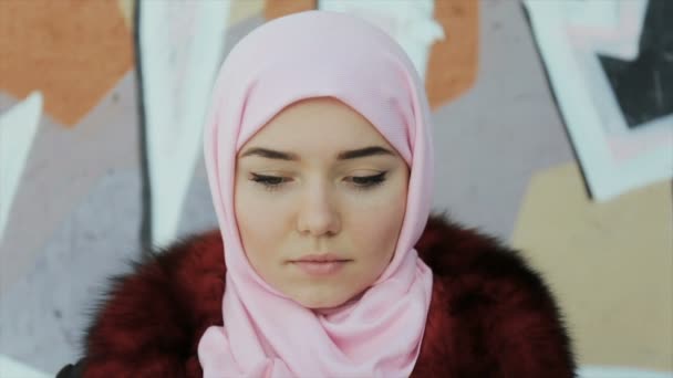 Portret van een Moslimvrouw met een sjaal gedekt hoofd op een muur achtergrond — Stockvideo