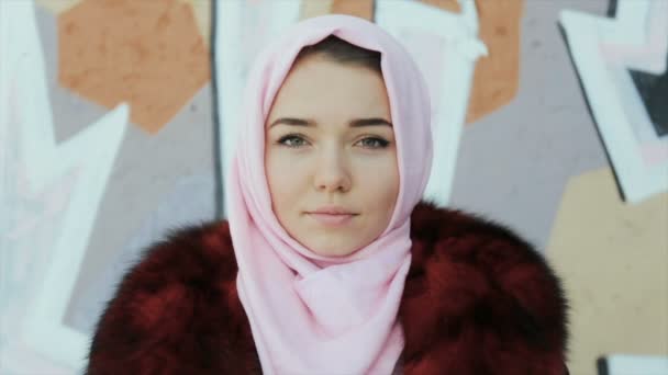 スカーフでイスラム教徒の女性の肖像画に壁の背景に頭が覆われています。 — ストック動画