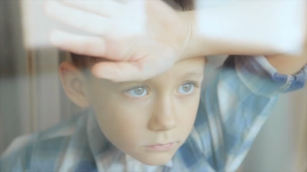 Un enfant triste regarde par la fenêtre — Video