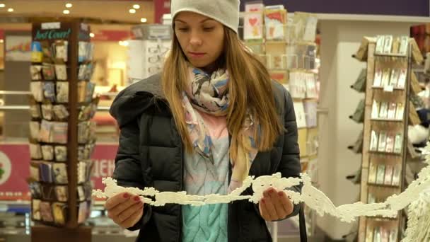 A young beautiful girl walks by the supermarket and chooses. Slow motion. — Stock Video