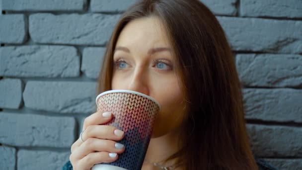 Una chica en un café bebe chocolate caliente de una taza de papel — Vídeos de Stock