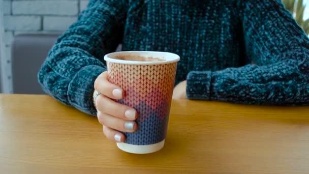 Bir kızın elinde sıcak bir cappuccino ile bir kağıt bardak. — Stok video