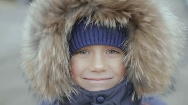 Retrato de un niño en chaqueta de invierno con capucha en la cabeza — Vídeo de stock