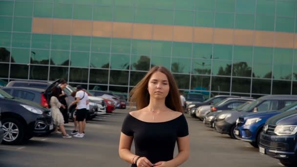 Kamera podąża za młodą atrakcyjną brunetką na parkingu. — Wideo stockowe