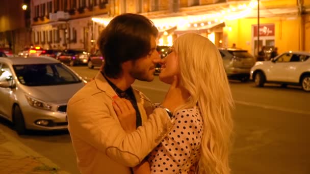 Casal romântico abraçando e beijando contra o pano de fundo de lanternas e vitrines da cidade noturna . — Vídeo de Stock