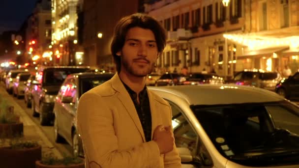 Portret van een bebaarde jonge man op de achtergrond van de nacht stad — Stockvideo