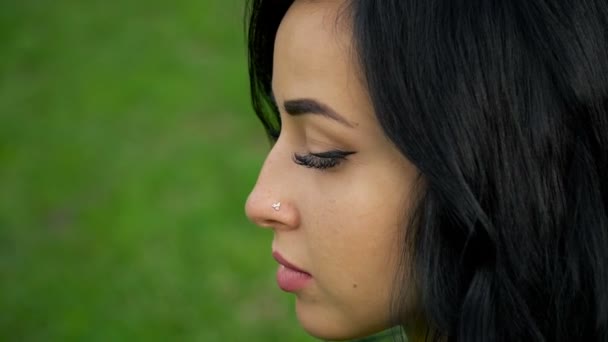 Retrato de uma morena em um fundo de grama verde . — Vídeo de Stock