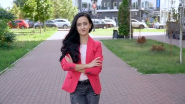 Açık güneşli bir günde bir şehir parkında kırmızı ceketli bir kadın.