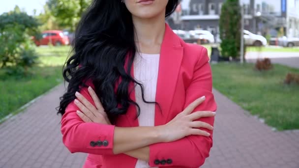 Een vrouw in een rood jasje in een stadspark op een heldere zonnige dag. — Stockvideo