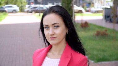 Açık güneşli bir günde bir şehir parkında kırmızı ceketli bir kadın.