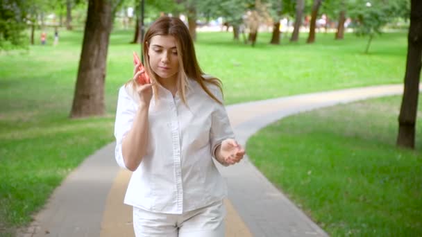 Chica utiliza un teléfono inteligente en el parque de verano — Vídeos de Stock