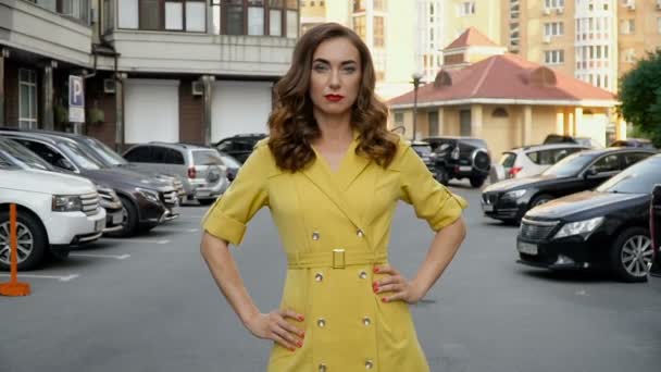 Menina em um vestido amarelo posando no estacionamento. Fiação da câmera de cima para baixo — Vídeo de Stock