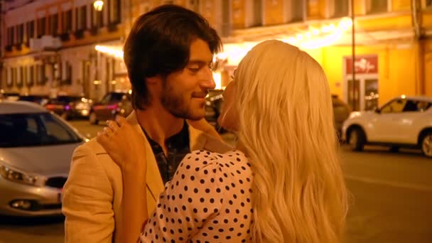 Casal romântico abraçando e beijando contra o pano de fundo de lanternas e vitrines da cidade noturna . — Vídeo de Stock