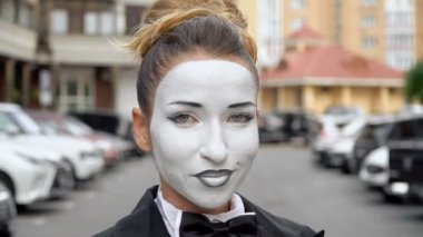 Siyah elbise ceket bir pandomim kız kamera için pozlar.