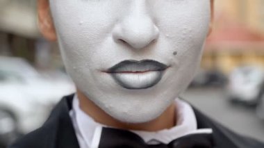 Siyah elbise ceket bir pandomim kız kamera için pozlar.