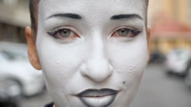 Siyah elbise ceket bir pandomim kız kamera için pozlar.