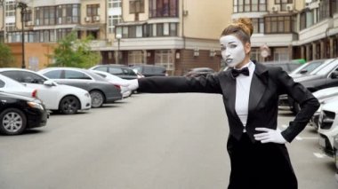 Siyah elbise ceket bir pandomim kız kamera için pozlar.