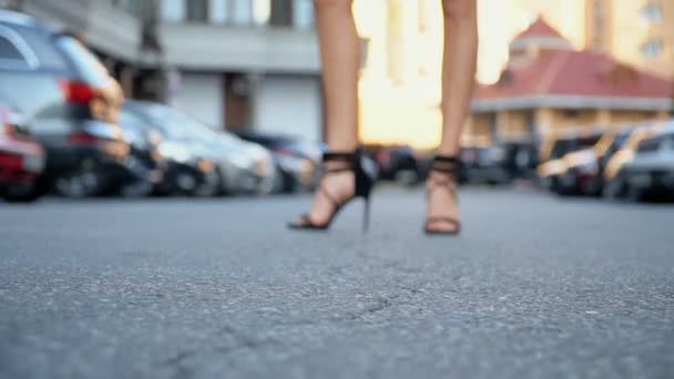 Schlankes Mädchen im schicken schwarzen Kleid posiert auf dem Parkplatz. Kameraverkabelung von unten nach oben — Stockvideo