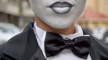 Siyah elbise ceket bir pandomim kız kamera için pozlar.