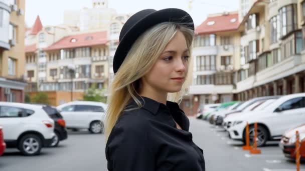 Retrato de una chica con una sonrisa chic en un sombrero negro — Vídeo de stock