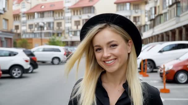 Portret van een meisje met een chique glimlach op een achtergrond van het parkeren — Stockvideo