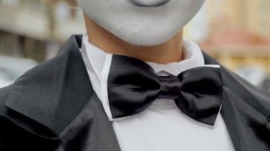 Siyah elbise ceket bir pandomim kız kamera için pozlar.