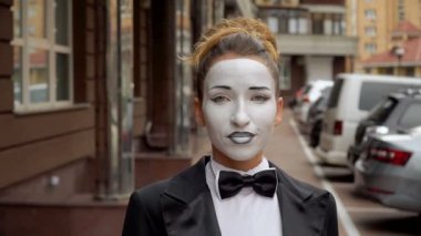 Siyah elbise ceket bir pandomim kız kamera için pozlar.