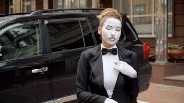 Siyah elbise ceket bir pandomim kız kamera için pozlar.